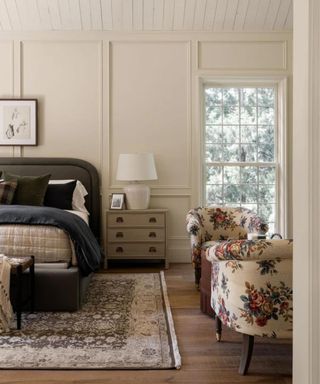 neutral bedroom with a large rug dark velvet bed and a floral seating area