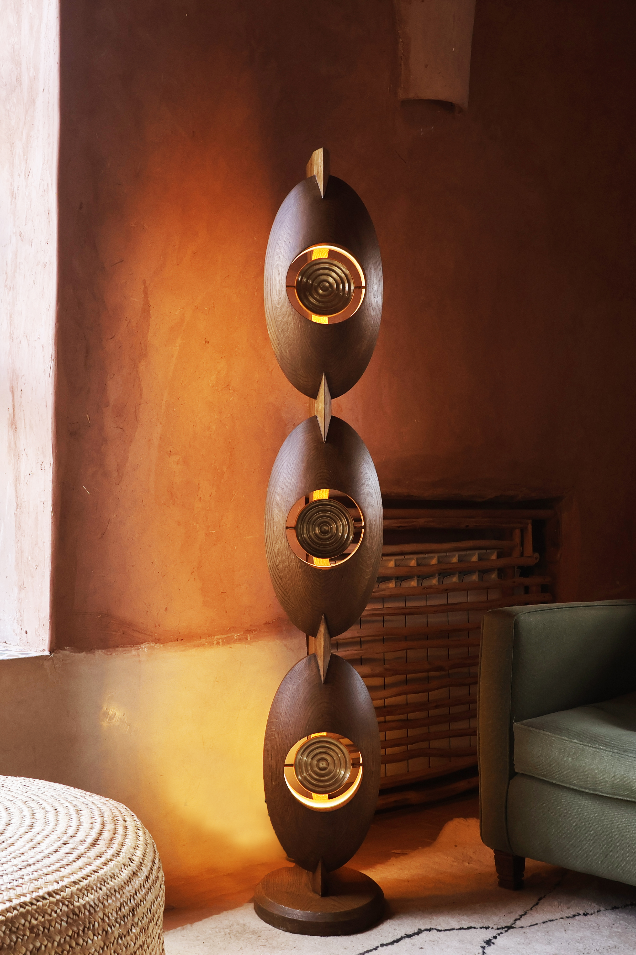 Standing circular lamp near arm chair and brown wall