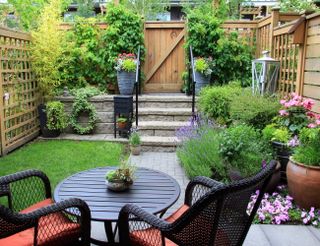 A garden patio with outdoor furniture and potted plants clearly divided into neat zones for fully functional use