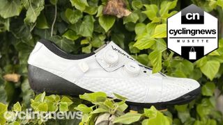 A white Bont Vaypor S Li2 shoe perched against a leafy bush