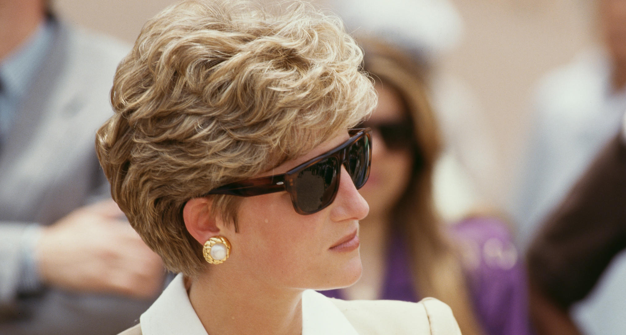 Princess Diana wearing sunglasses and a tan blazer looking to the right