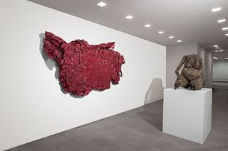A piece of abstract artwork in red, and a sculpture of a naked female torso