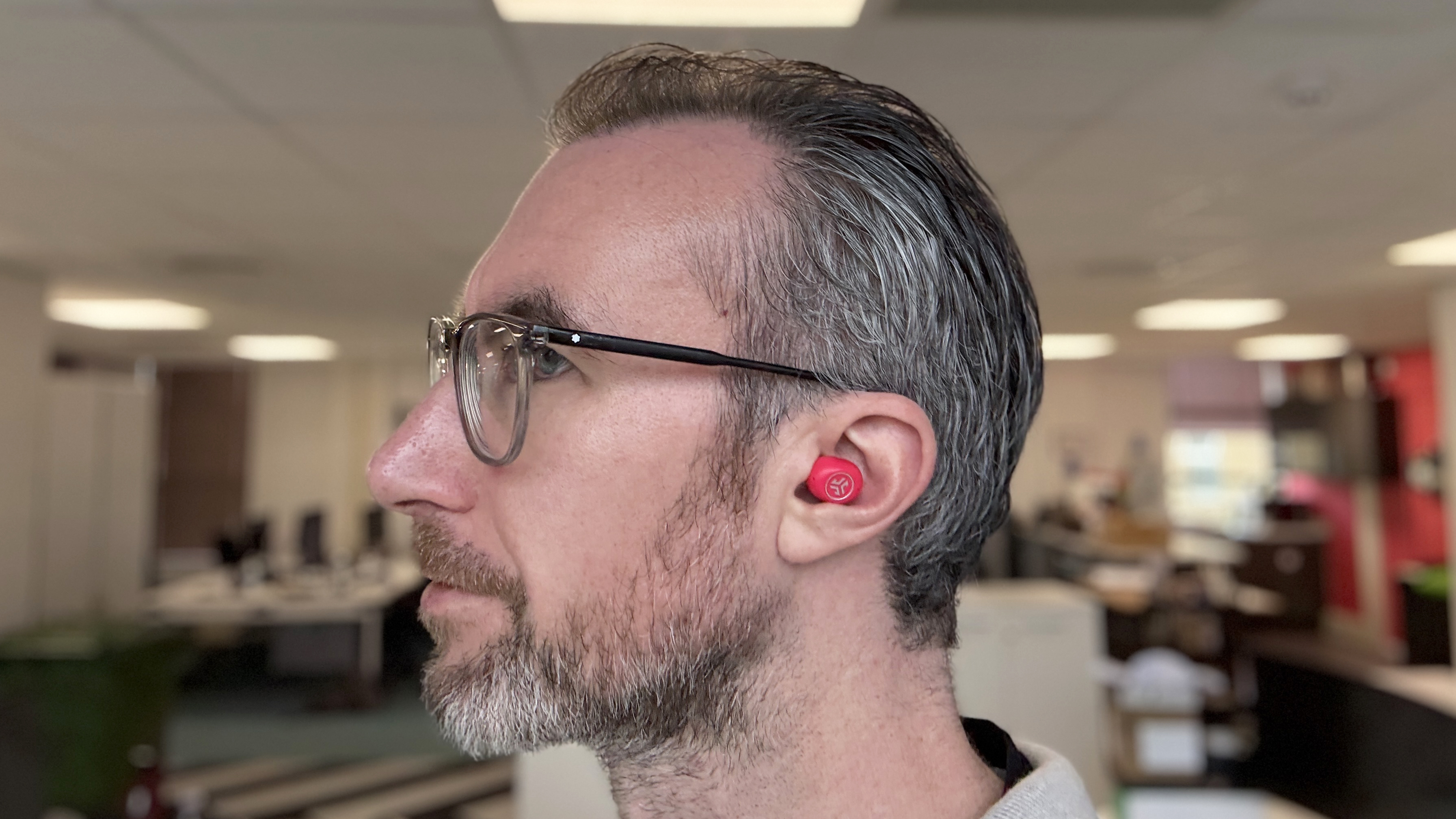 JLab JBuds Mini ANC earbuds worn by a man in an office