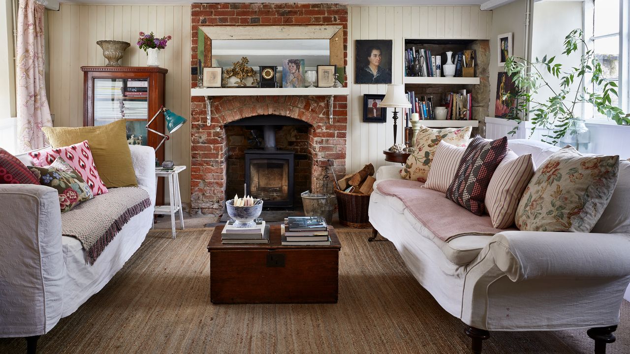 country style living room with brick fireplace and woodburner, pale walls and neutral sofas with scatter cushions