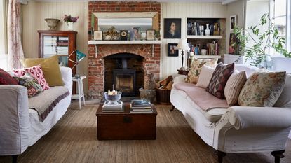 country style living room with brick fireplace and woodburner, pale walls and neutral sofas with scatter cushions