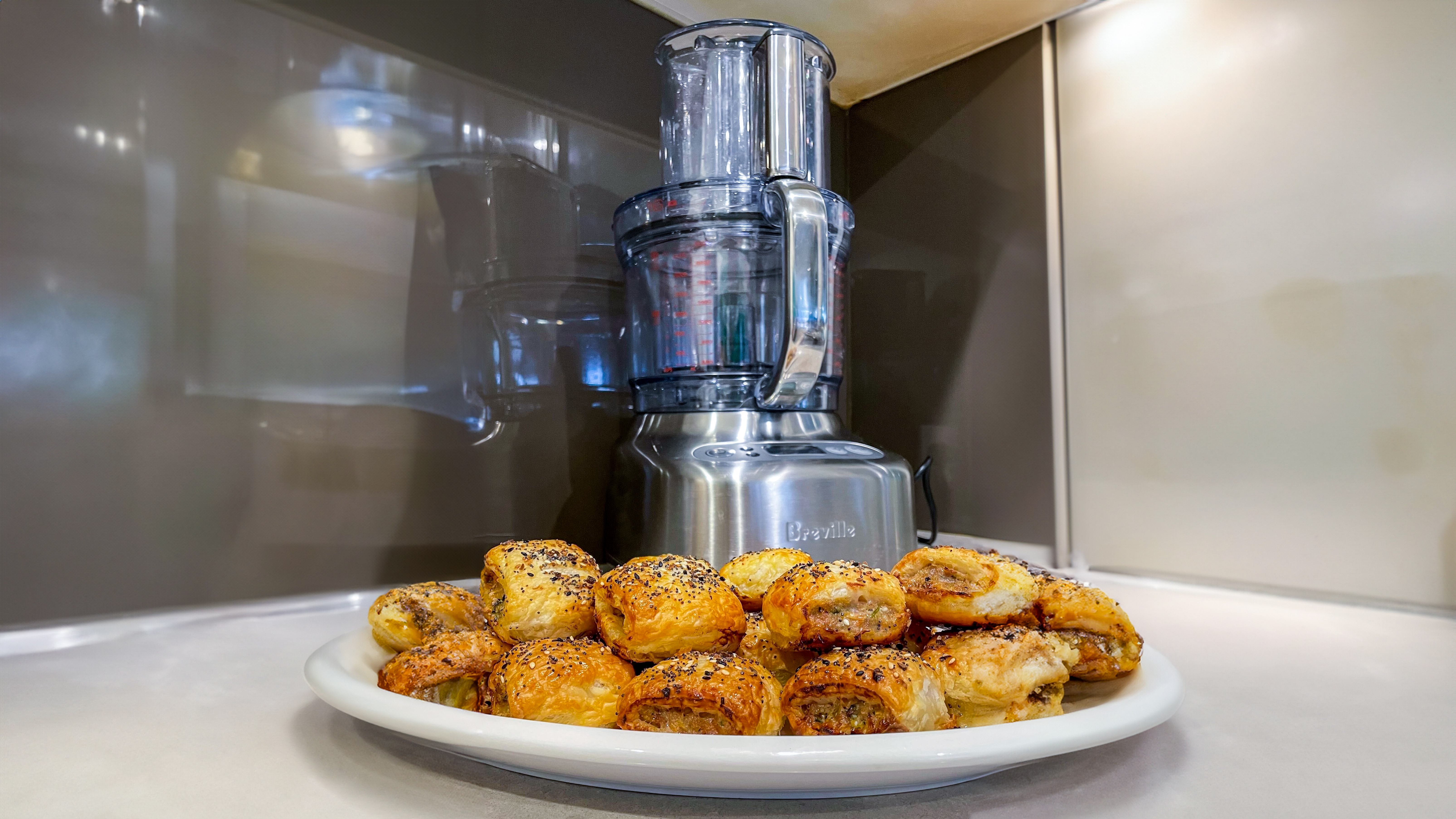 A plate of homemade sausage rolls in front of the Breville Paradice 16 food processor
