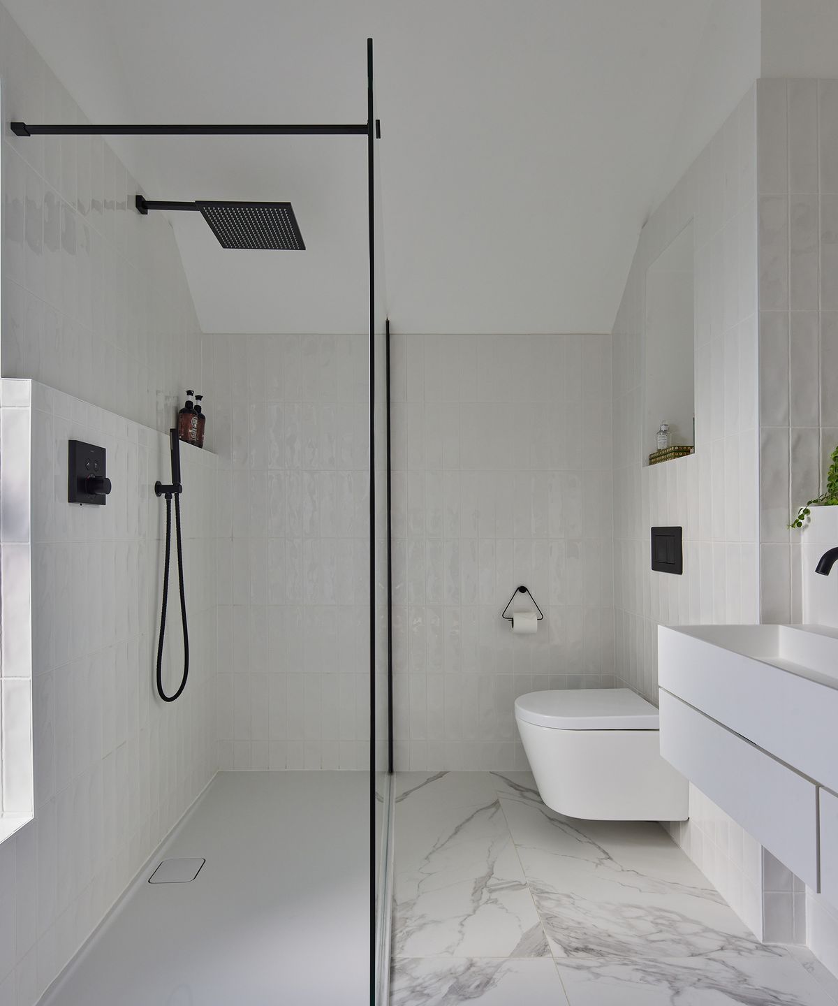 Ensuite bathroom with white tiling and walk in shower. The fixings are in a contrasting black