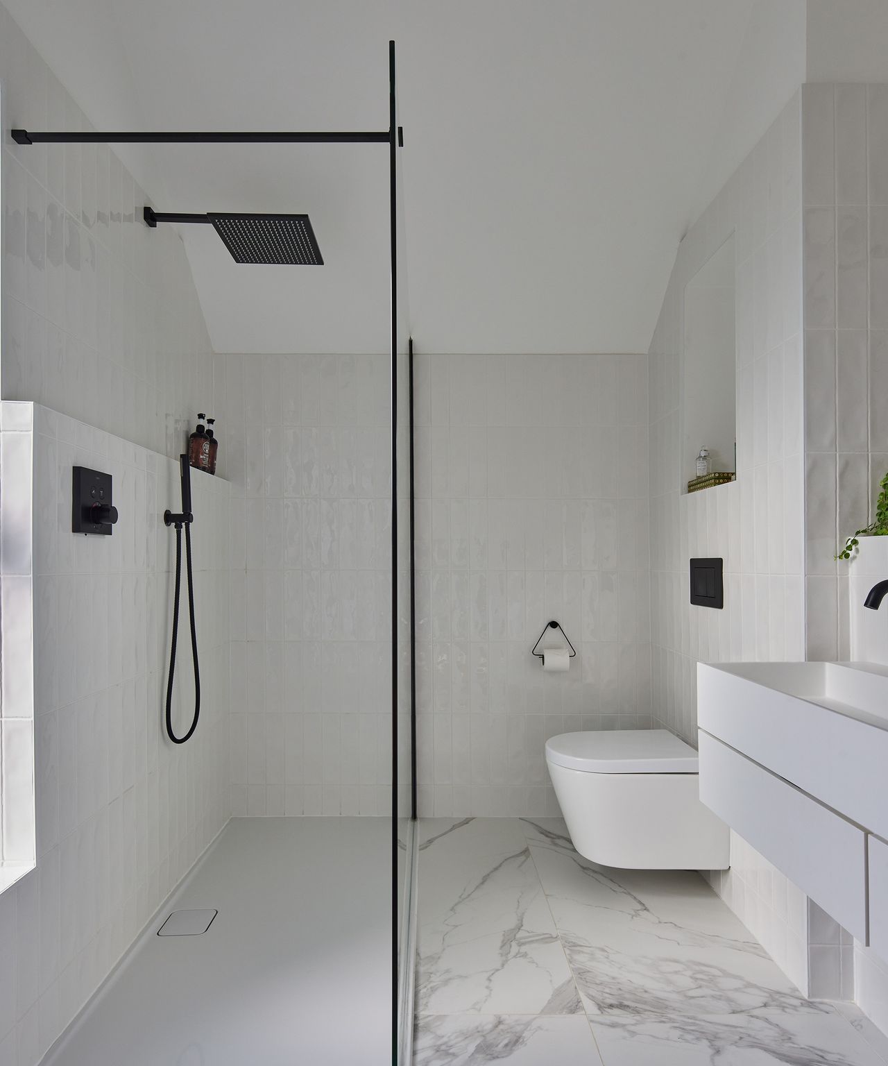 Ensuite bathroom with white tiling and walk in shower. The fixings are in a contrasting black