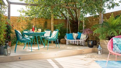 Decked outdoor space with slatted fence and turquoise dining table and chairs