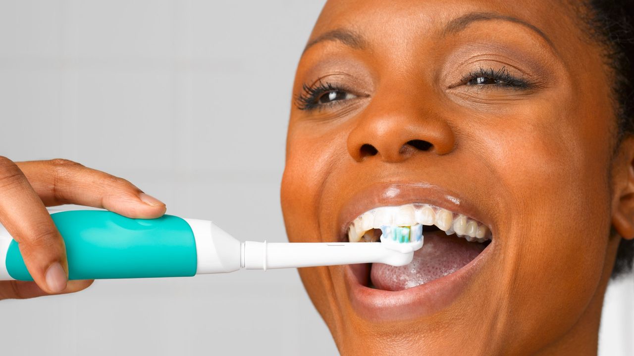 woman using electric toothbrush