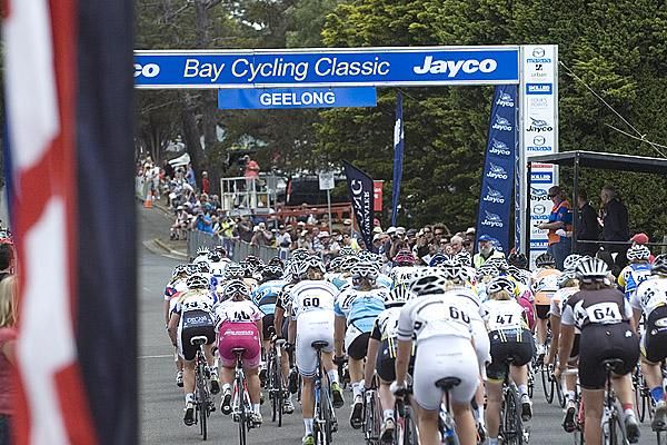 The peloton in the womens' race make their way beneath the banner in Geelong's Eastern Gardens.