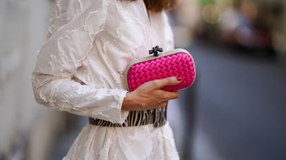 Therese Hellström wears a white gathered/pleated dress with embroidery and shoulder pads from H&M, a large black and white zebra print pattern belt, a Bottega Veneta pink bag and red jelly nails