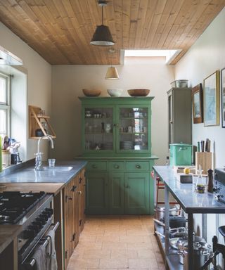 small kitchen with freestanding cabinetry, green painted cabinet with glazed doors, zinc countertops, bare wood shiplap ceiling, cream walls