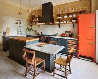 Farmhouse kitchen with split level island and orange fridge