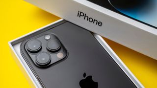 iPhone 14 Pro Max in its box on a yellow background