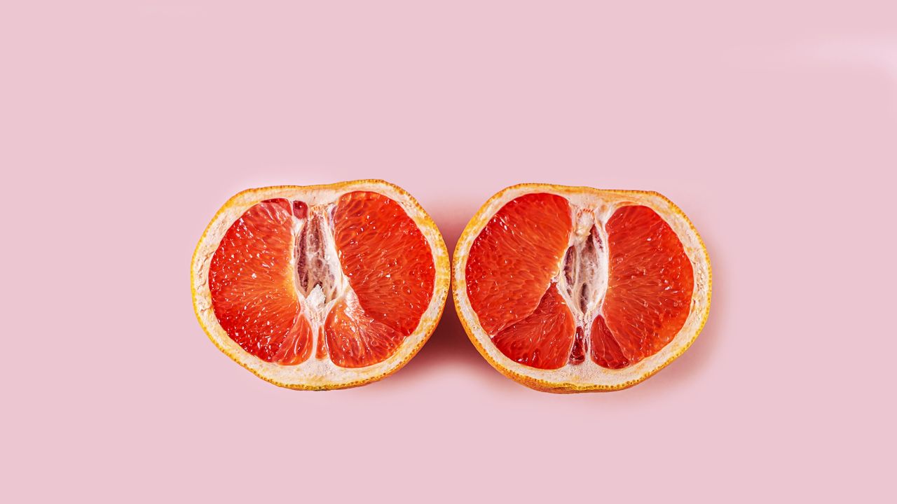 grapefruit cut in half on pink background 