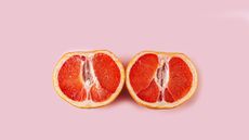 grapefruit cut in half on pink background 