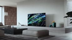 The Sony A95L TV in a light coloured living room sitting on a shelf