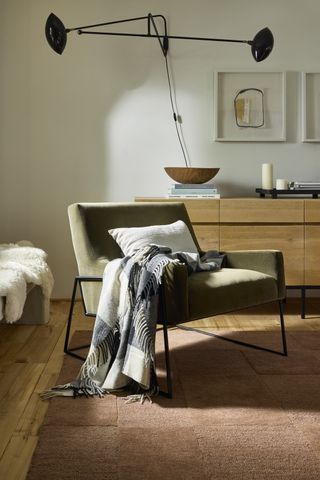 Shot of a living room corner with an orange rug and an olive green accent chair