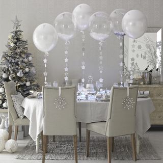 White dining room with table and chairs decorated for Christmas with balloons on the table