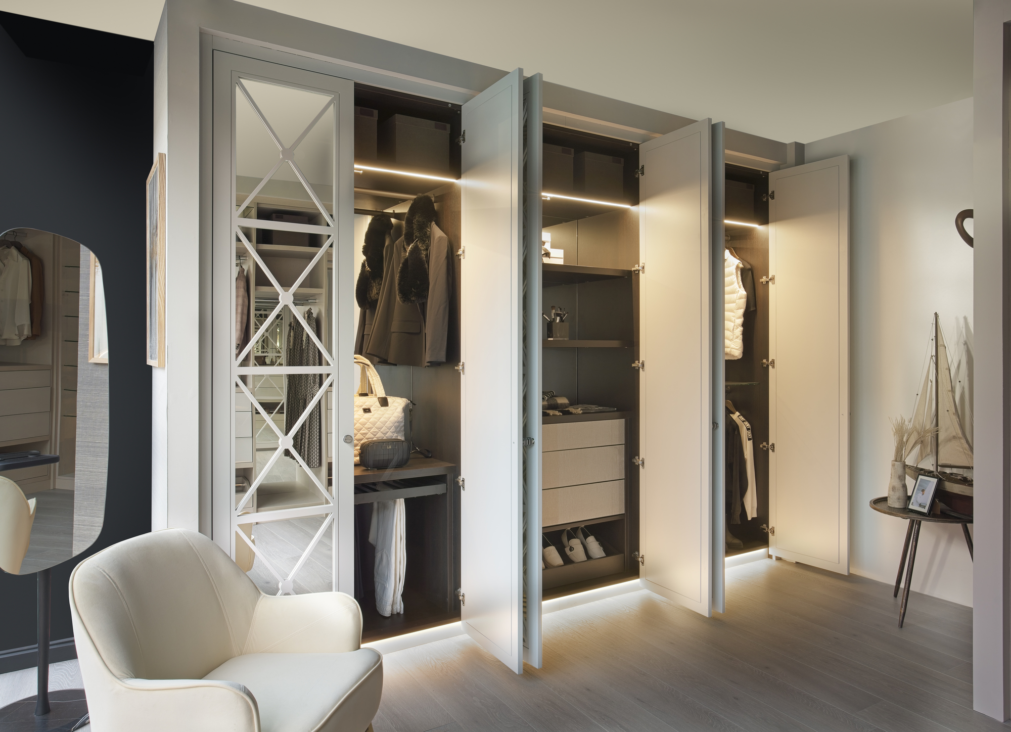 A white, built-in closet with open doors displaying organized clothes, shelves, and storage boxes