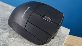 A photo of the Contour Unimouse on a stone surface and a wooden desk, all set against a dark blue background.