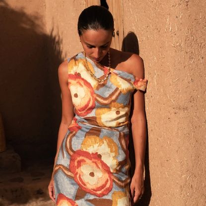 Model wearing a SIR. dress leaning against a wall