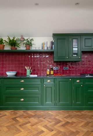 Jewel-toned kitchen with emerald green cabinetry and cranberry-colored tile on the backsplash.