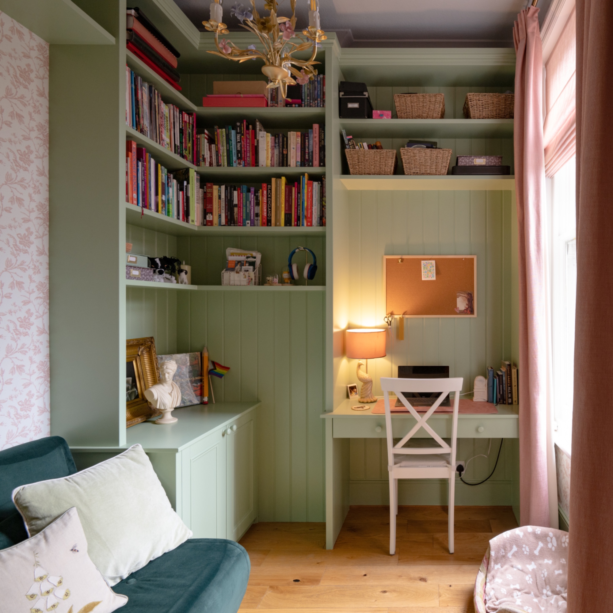 green home office with floor to ceiling storage, desk and sofa bed