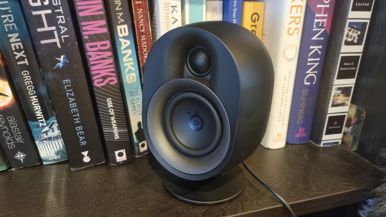 The rear left satellite speaker of the SteelSeries Arena 9 on a bookshelf