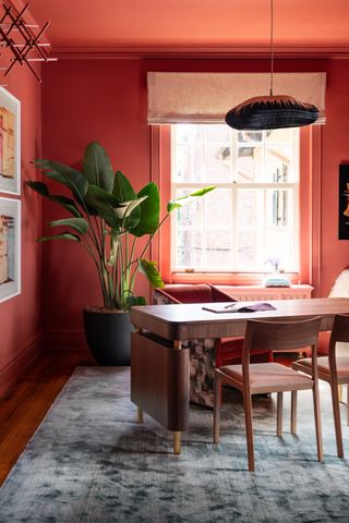 A home office painted red with a dark wood floor and furniture