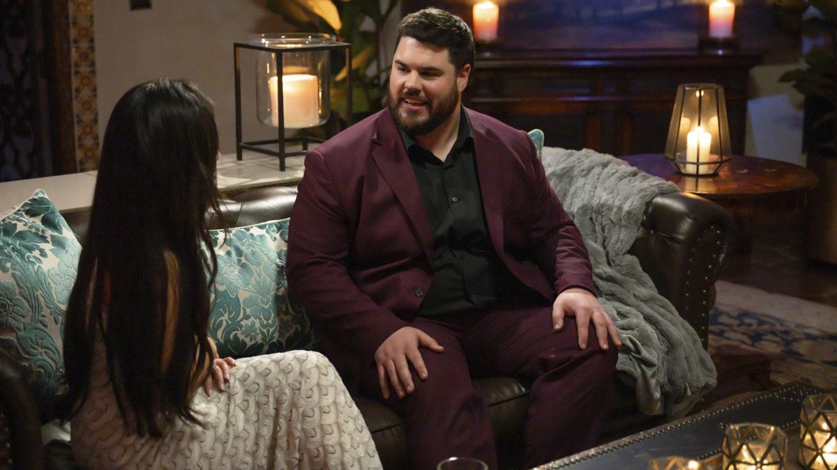 Brett Harris sits on a couch talking to Jenn Tran during The Bachelorette&#039;s Season 21 premiere on July 8, 2024.