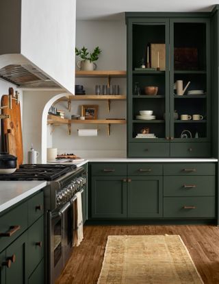A kitchen with cabinetry painted in a deep forest green shade