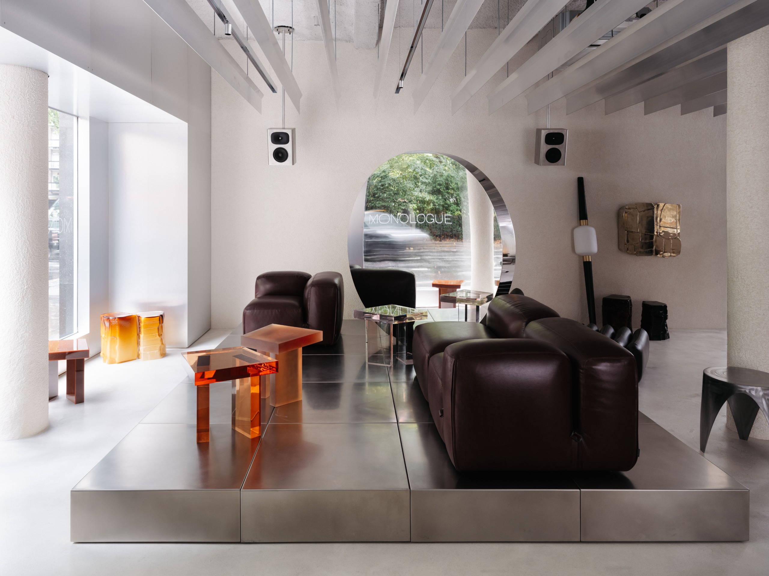 a showroom with a large leather sofa and perspex colored tables