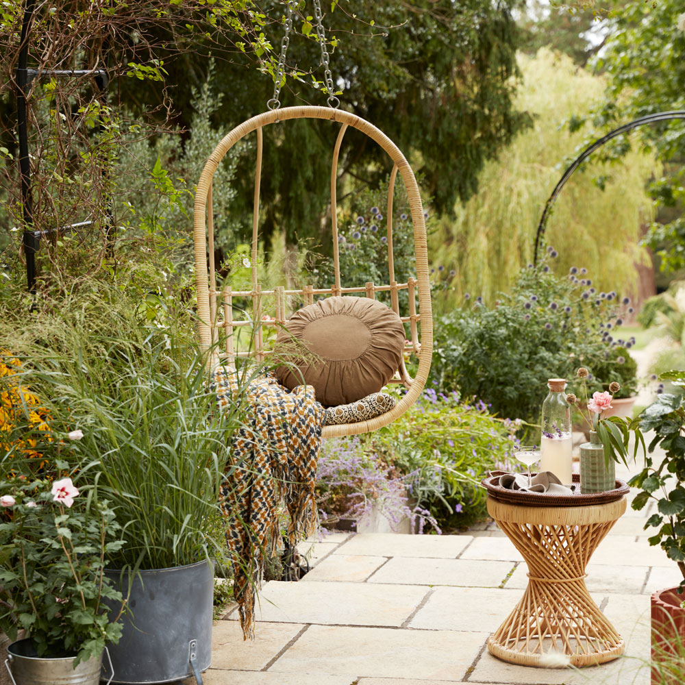 hanging chair in patio garden area surrounded by potted plants