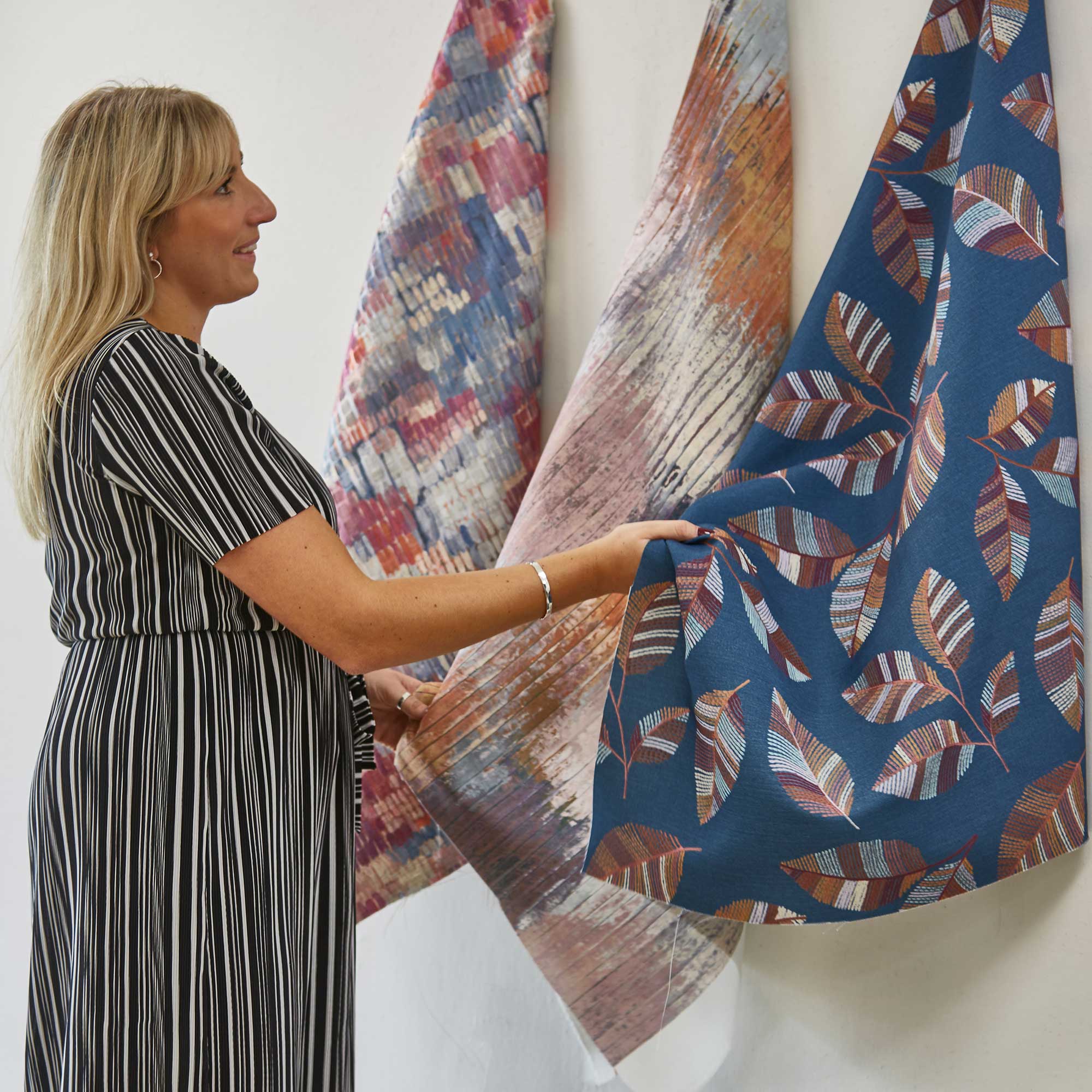 Marie Goodwin looking at hanging fabrics