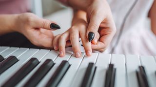 A piano teacher showing a child how to position fingers on a keyboard