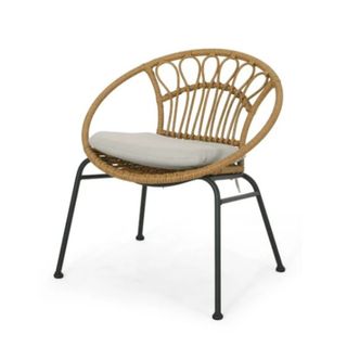 A curved rattan chair with a gray throw pillow and black iron legs