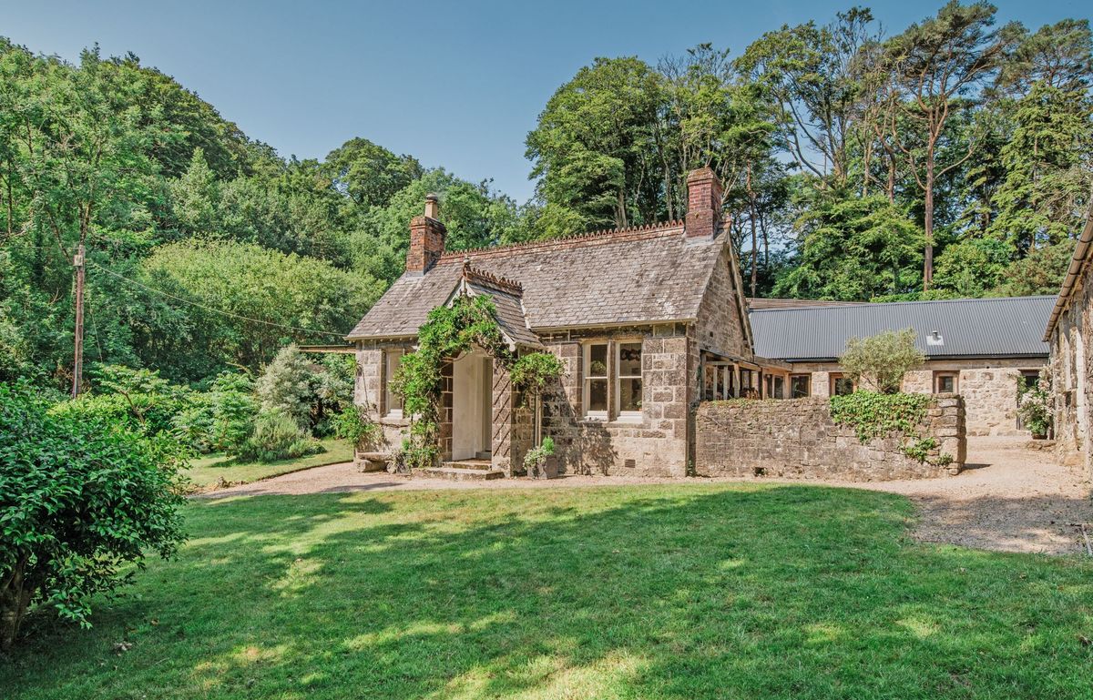 A stone building is at the front of the property which has a grassy front garden
