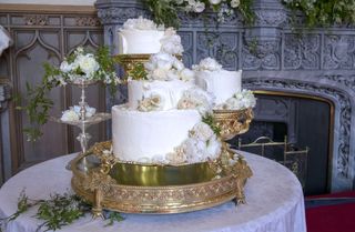 Prince Harry and Meghan Markle's white wedding cake covered in flowers sitting on a gold stand