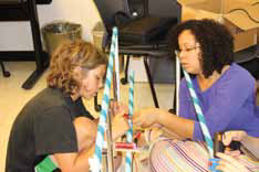 A student and teacher work on an electro-mechanical music machine.