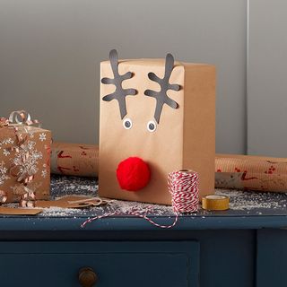 Christmas present wrapped in brown paper with fluffy reindeer nose