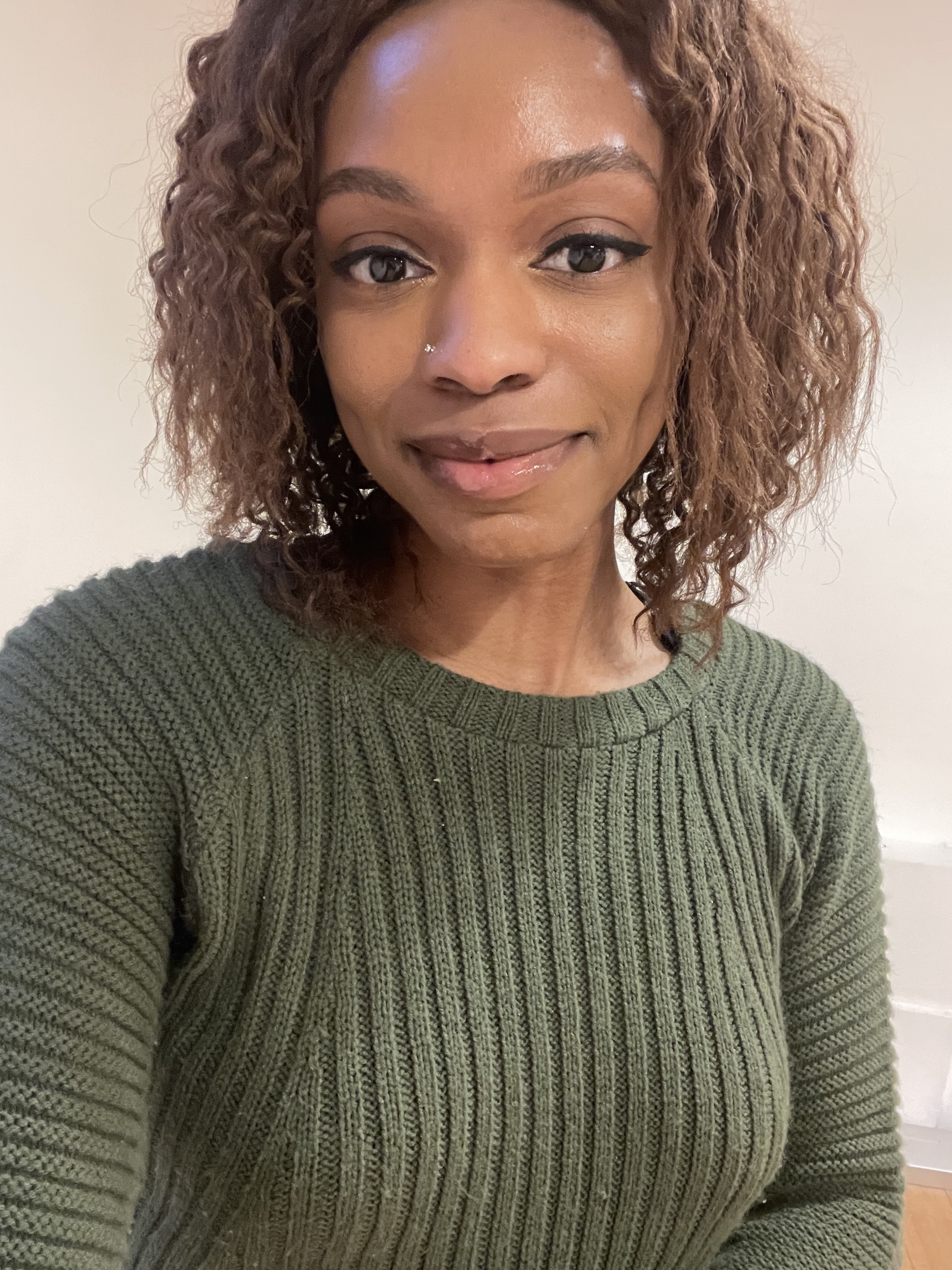 A girl with curly brown hair and makeup with plump lips testing a new Patrick Ta tinted lip balm launch.