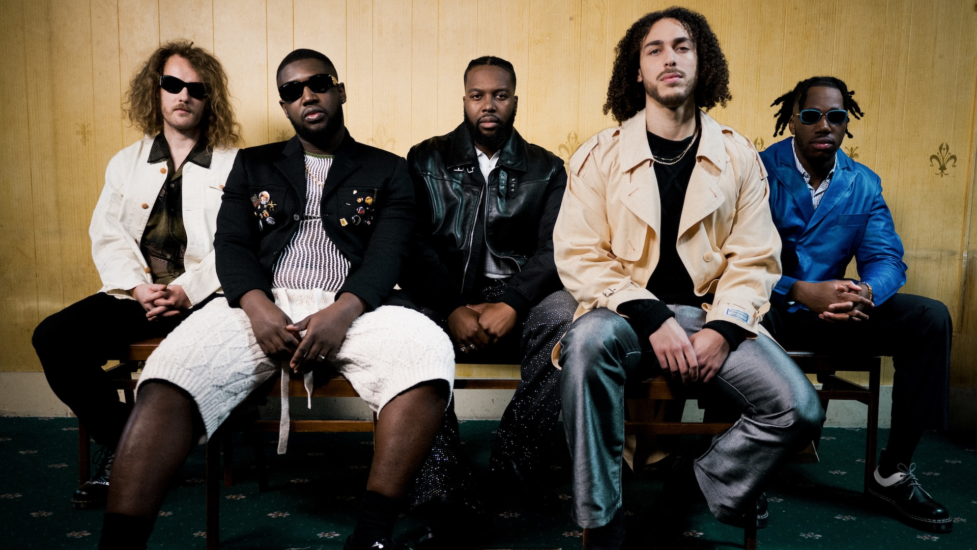 The Ezra Collective sat on a bench