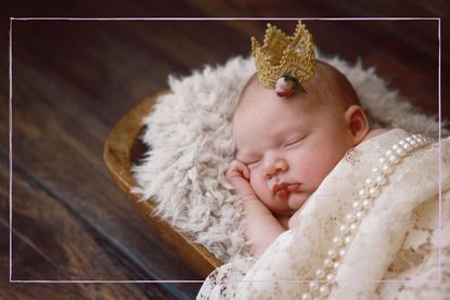 A newborn baby asleep wearing a crown