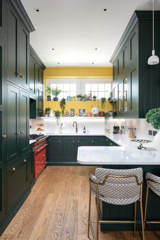 Kitchen with green cabinets and peninsular unit, wood floor, and yellow wall