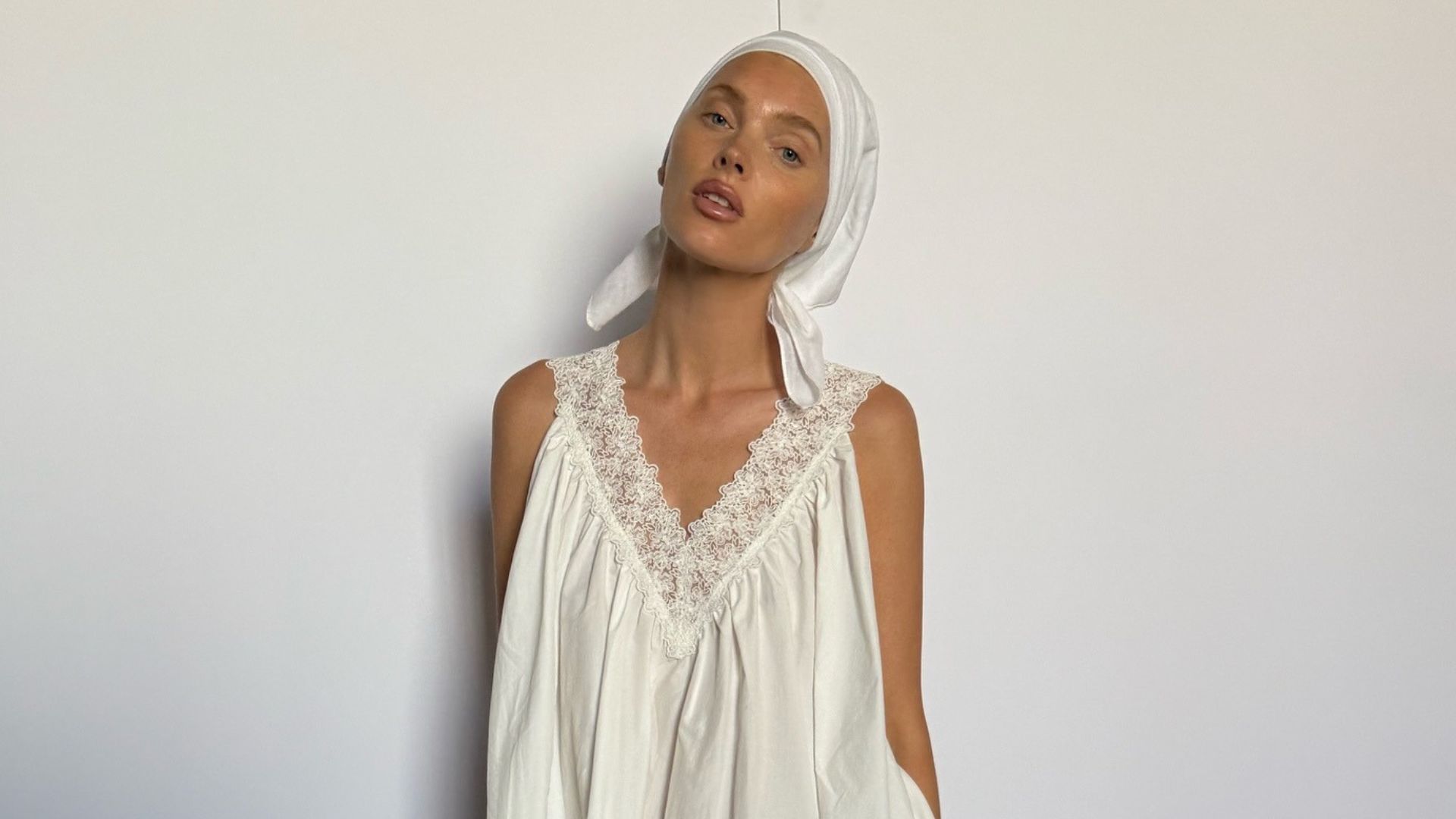 Elsa Hosk wears a white sleeveless minidress with black biker boots and a white headscarf.