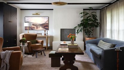 An organic modern style living room with a blue sofa, a large wooden coffee table, and a Samsung Frame TV in the corner of the room 
