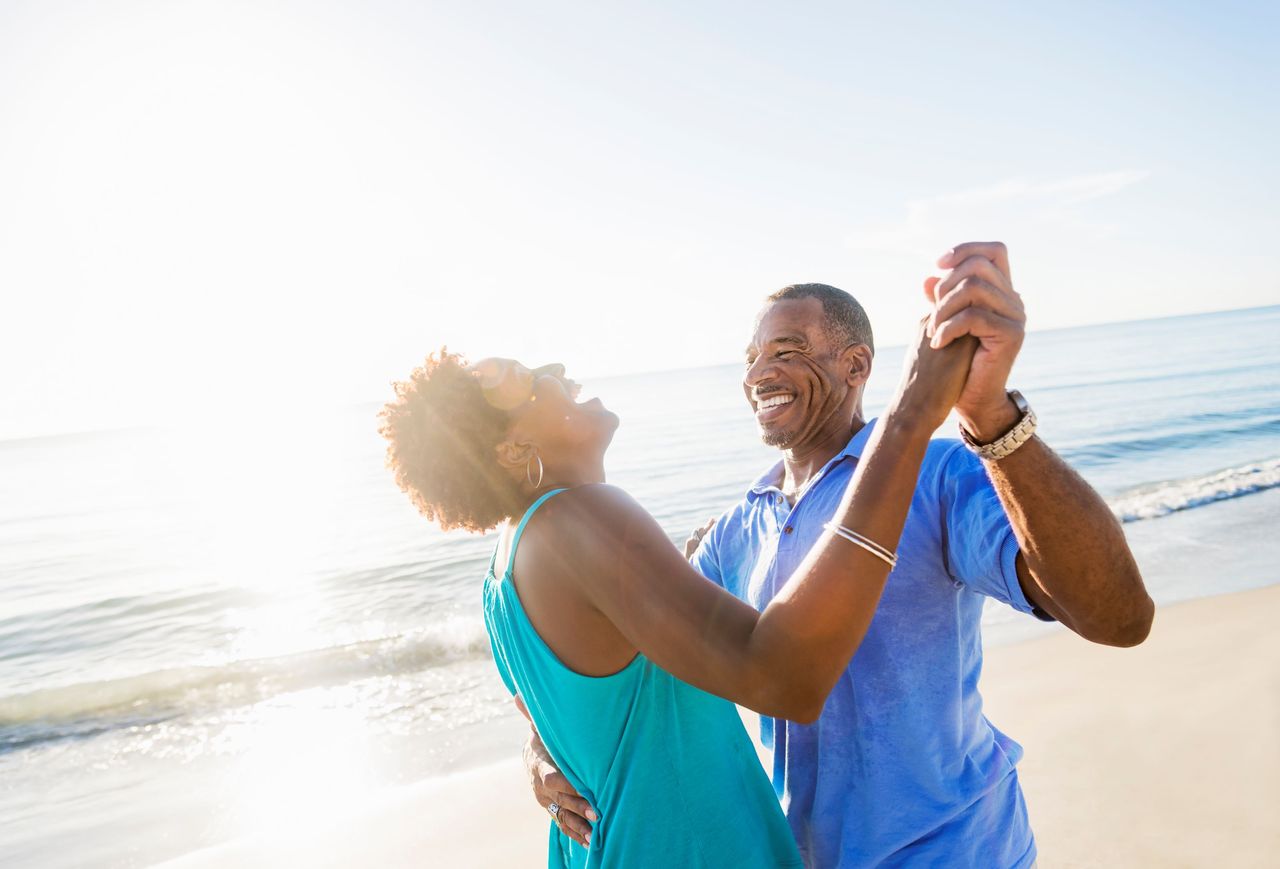 A couple laughs and dances on a beach. 