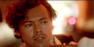 Harry Styles driving a car with cool lighting.